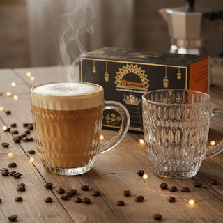 Two glass mugs with steaming coffee and a box of coffee beans on a wooden surface.